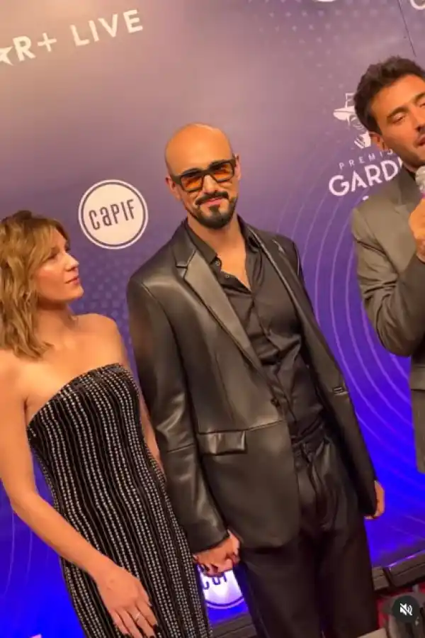 ABEL PINTOS. Anteojos ahumados y cuero negro, de la mano de Mora Calabrese, su esposa, de strapless bordado en piedras. 