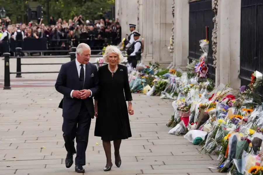 El rey Carlos y la reina Camila de Gran Bretaña caminan a lo largo de la valla del Palacio de Buckingham, tras el fallecimiento de la reina Isabel. Foto de Reuters