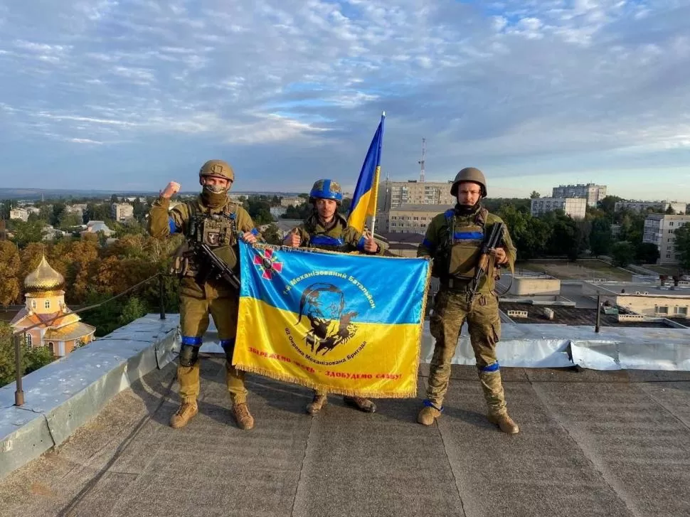 EL QUIEBRE. Soldados ucranianos sostienen una bandera en una azotea en Kupiansk. Sin esa ciudad, el los rusos perdieron la línea de abastecimiento. 