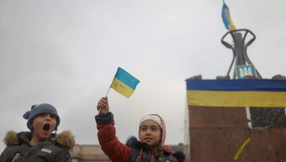 CELEBRACIÓN. Dos niños flamean una bandera de Ucrania para festejar la salida del ejército de Rusia. 
