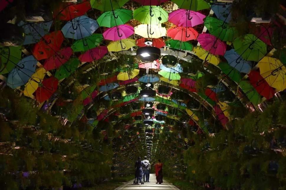 UN PASEO DIFERENTE. Turistas recorren una especie de galería que tiene decenas de paraguas que generan una reparadora sombra en el calor qatarí. 