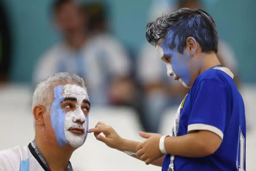 GRANDES Y CHICOS. Un nene aplica maquillaje en el rostro de su papá.