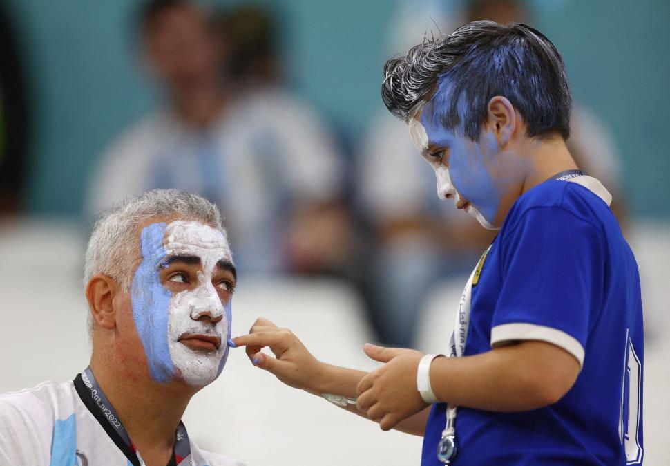 GRANDES Y CHICOS. Un nene aplica maquillaje en el rostro de su papá.