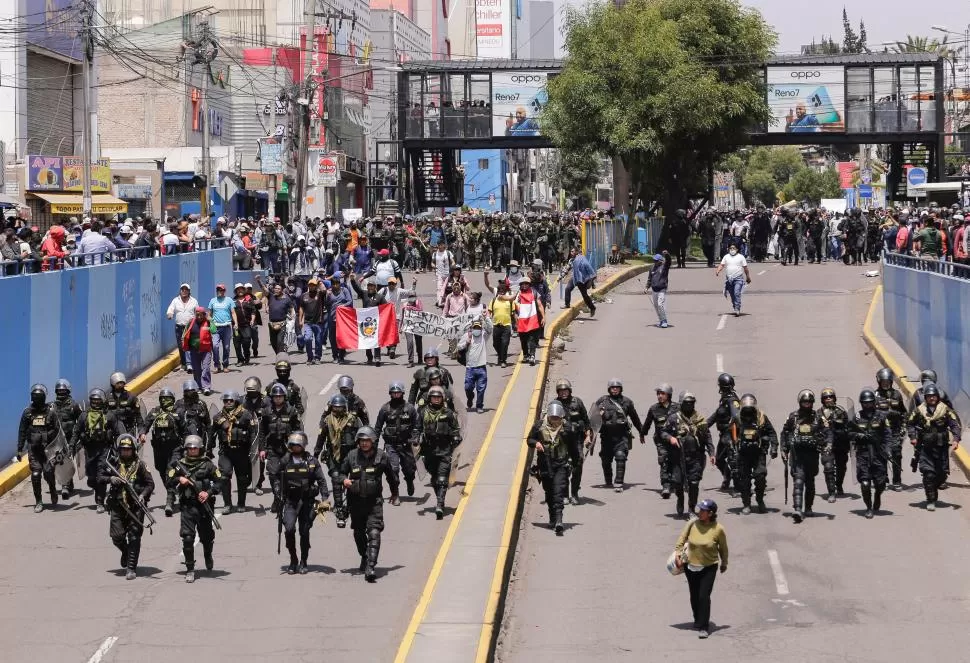 TENSIÓN EXTREMA. Con armas y equipo antidisturbios, la policía de Arequipa camina junto a manifestantes que demandan la liberación de Castillo. 