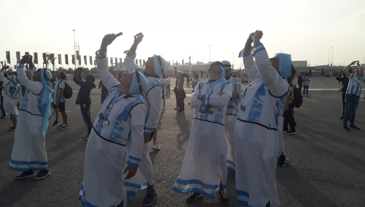 PARA ARRIBA. Los simpatizantes tratan de enfocar alguno de los aviones que sobrevuelan Lusail. 