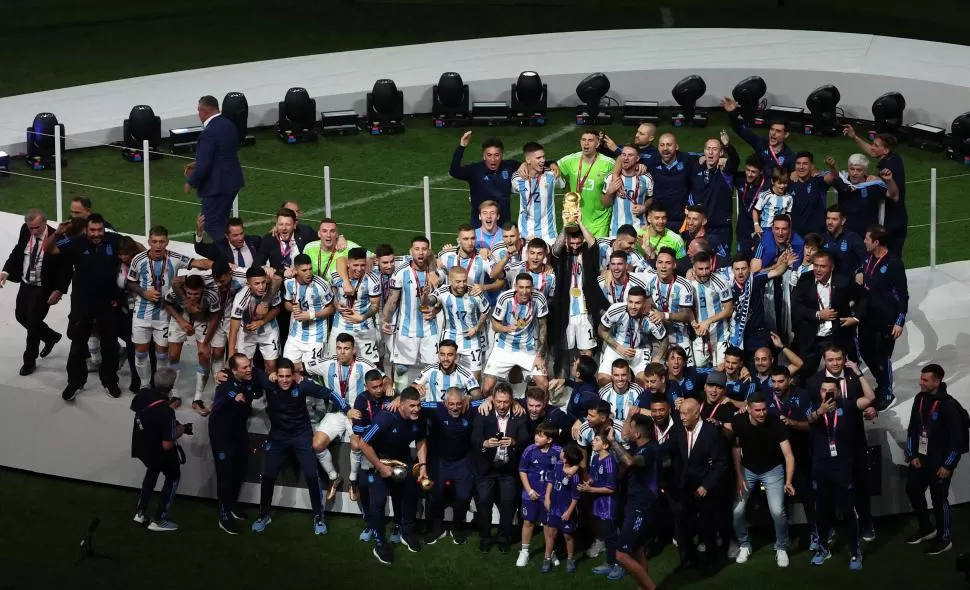 TODOS PARA LA FOTO FINAL. Jugadores, cuerpo técnico, colaboradores, familiares posan con Messi que levanta el trofeo. Fue el equipo ganador completo. reuters
