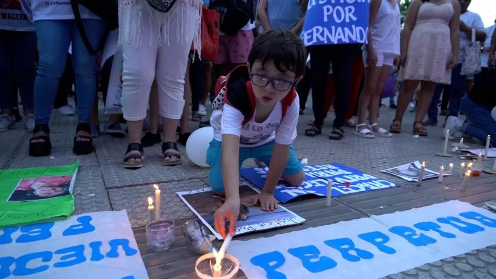 RECLAMO ILUMINADO. Un chico enciende una vela junto a un cartel que exige perpetua para los asesinos. la gaceta / fotos de martín burgos