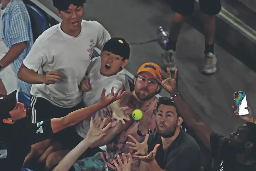 EL QUE LA AGARRA SE LA QUEDA. Espectadores intentan atrapar la pelota durante el partido entre Taylor Fritz y Nikoloz Basilashvili.