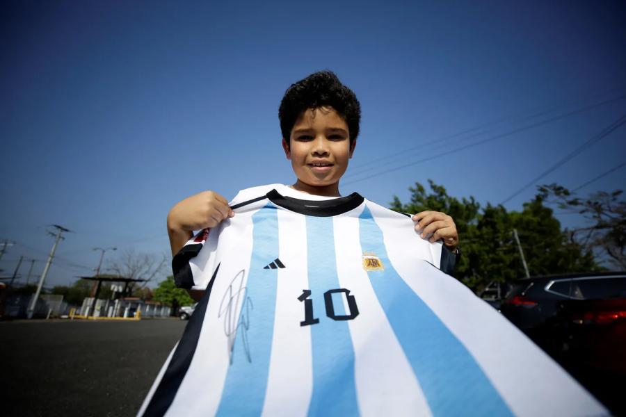 Un nene salvadoreño muestra su camiseta de la Selección argentina firmada por el DT nacido en Pujato. (Foto: EFE)