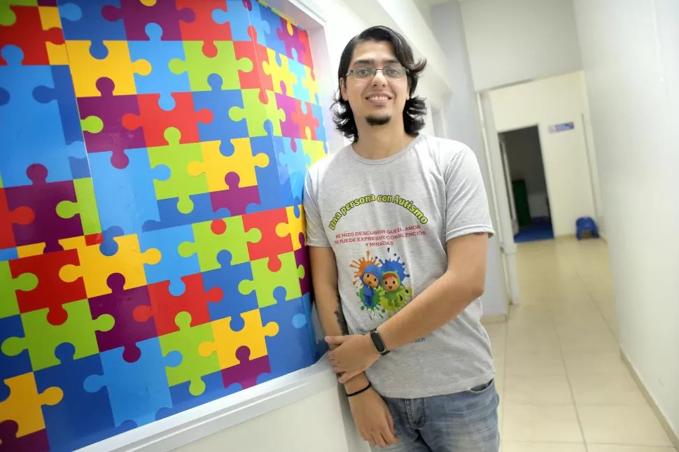 ÁMBITO LABORAL. Nicolás Spuches en su lugar de trabajo con una remera alusiva al TEA. 