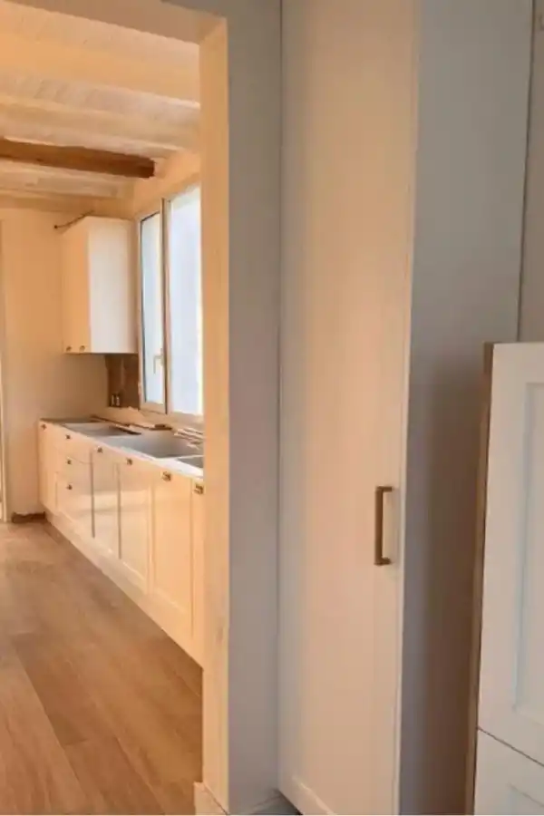 La cocina es bastante amplia y cuenta con muebles blancos.