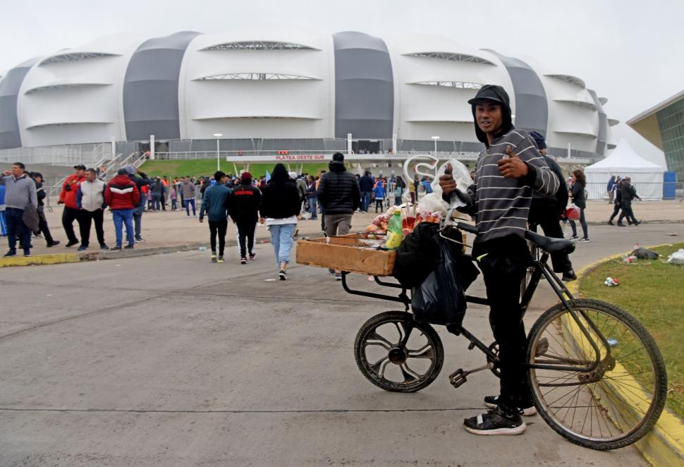 QUIOSCO MÓVIL. A bordo de su bicicleta, Damián Lobo es uno de los vendedores ambulantes que aprovechan el turismo mundialista para hacer unos pesos.