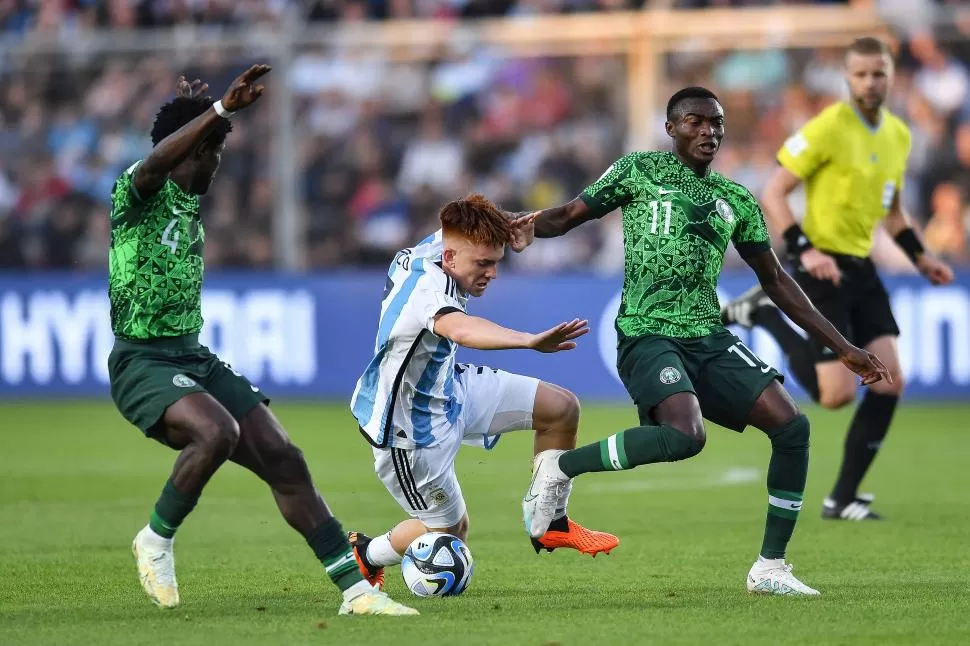 ESTA VEZ NO FUE GRAVITANTE. Valentín Barco trata de filtrarse entre la marca de Daniel Daga y de Ibrahim Muhammad, que fue el autor del primer gol nigeriano. 