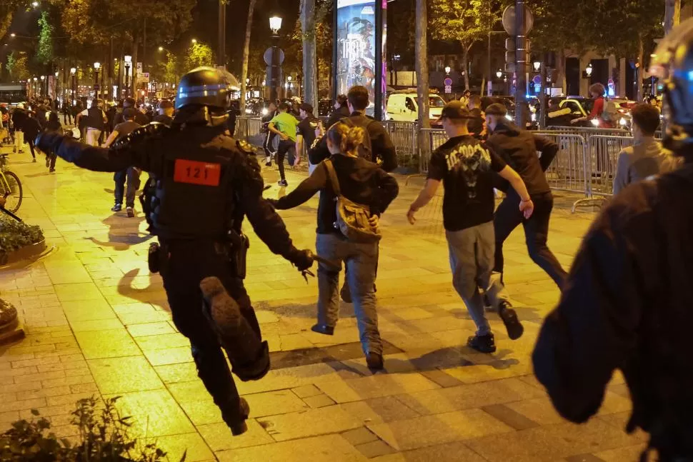 CARRERA EN PARÍS. Grupos de manifestantes escapan de la Policía por la avenida de los Campos Elíseos. 