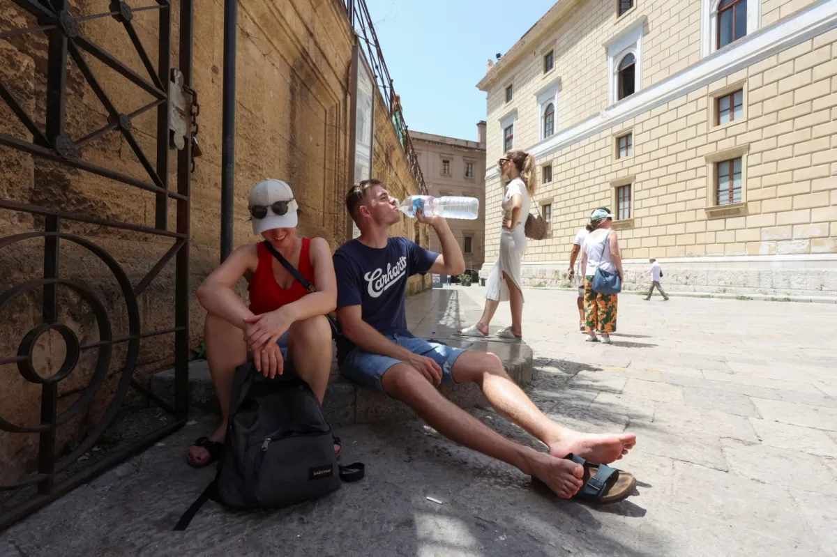 Turistas se sientan a la sombra para protegerse del sol durante una ola de calor, en Palermo, Italia. REUTERS