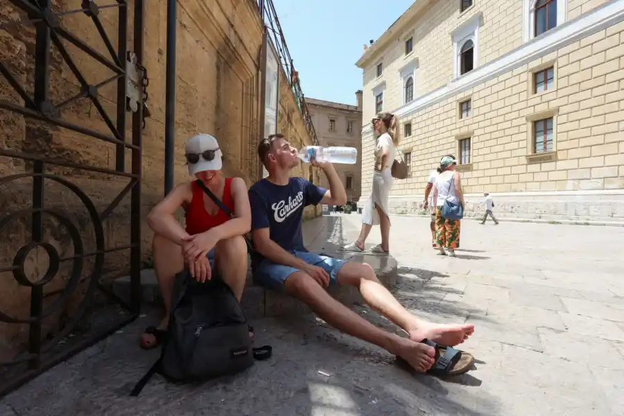 Turistas se sientan a la sombra para protegerse del sol durante una ola de calor, en Palermo, Italia. REUTERS