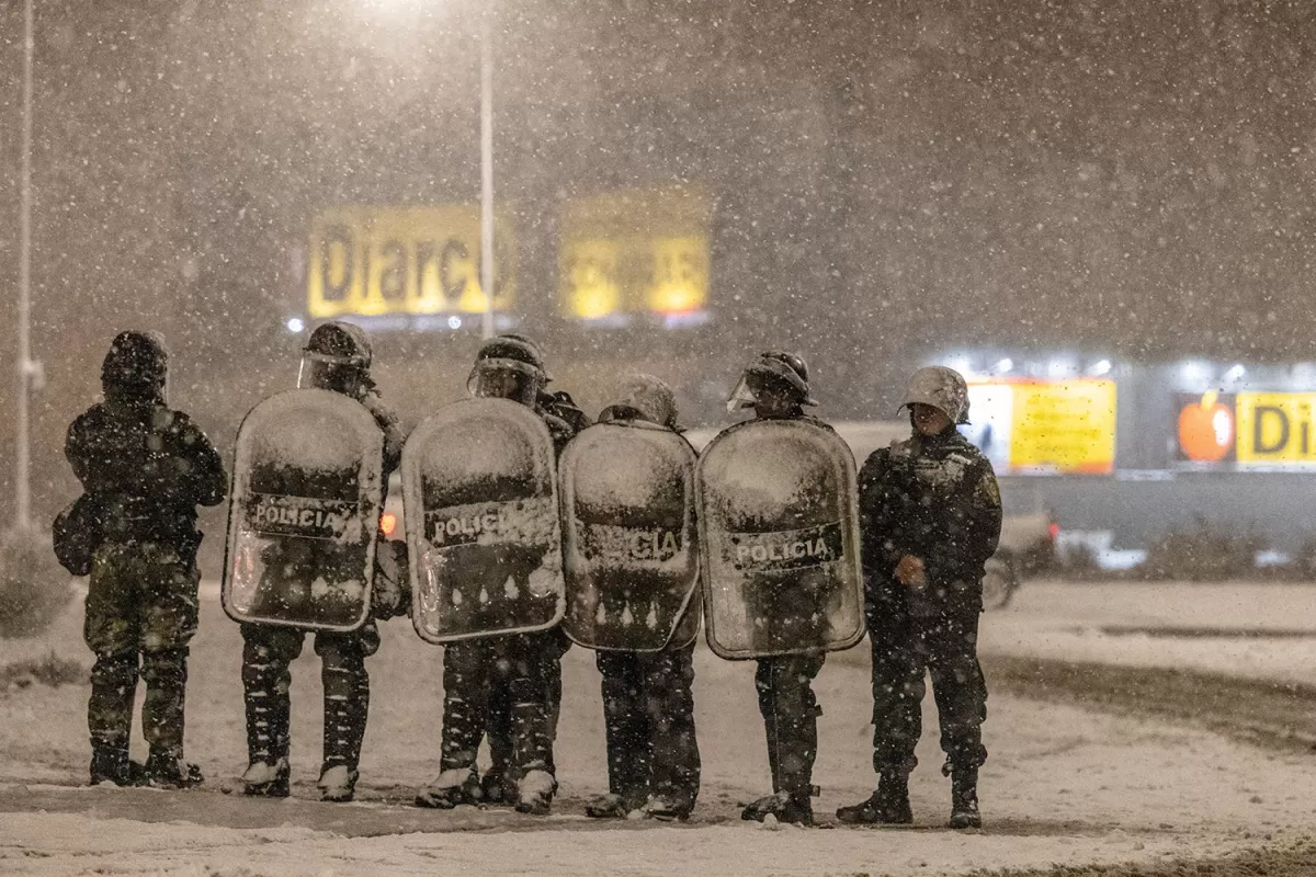 CUSTODIA. Policías forman fila bajo la nieve en las cercanías de un supermercado en Bariloche (Río Negro).
