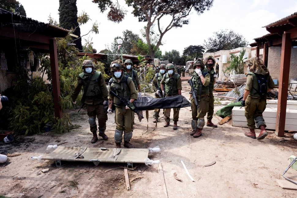 TRAGEDIA. Soldados israelíes llevan el cuerpo de una víctima del ataque 