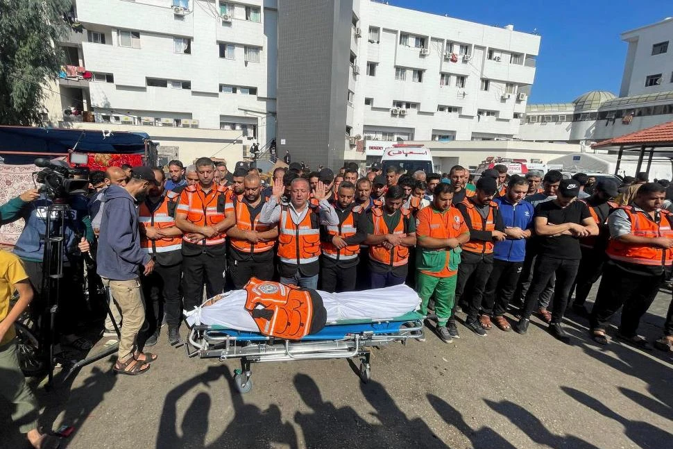 PLEGARIAS. Miembros de un equipo de emergencia del hospital de Shifa, en Gaza, rezan ante al cuerpo de su compañero muerto en un bombardeo. 