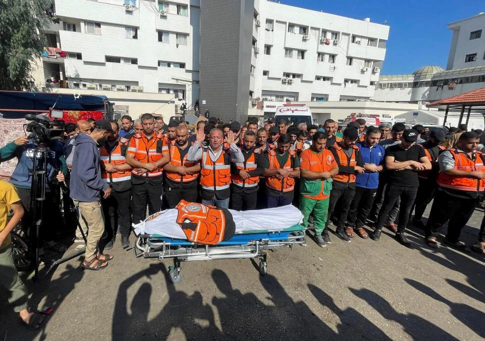 PLEGARIAS. Miembros de un equipo de emergencia del hospital de Shifa, en Gaza, rezan ante al cuerpo de su compañero muerto en un bombardeo. 