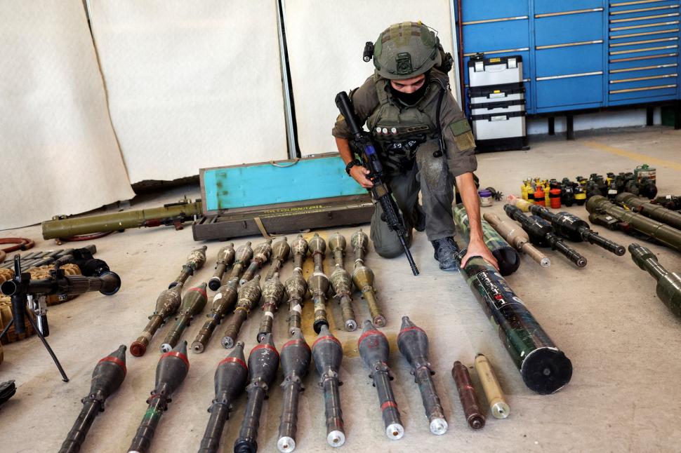 ARSENAL. Un militar israelí revisa las armas que dejaron atrás los combatientes de Hamas, después de su incursión en el sur de Israel, desde Gaza. reuters