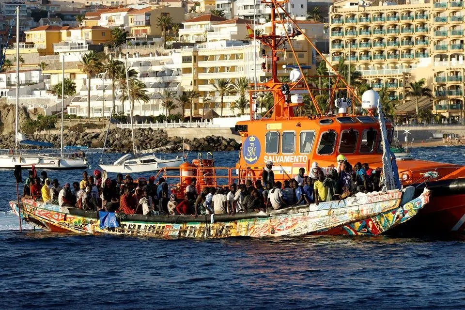 CRISIS. Un grupo de migrantes en un barco de madera son remolcados por un barco de la guardia costera española hasta el puerto de Arguineguin, en la isla de Gran Canaria.