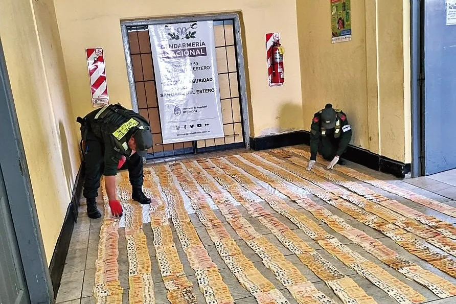 IMPACTANTE IMAGEN. Gendarmes acomodan en el piso de una habitación los billetes secuestrados en un operativo.