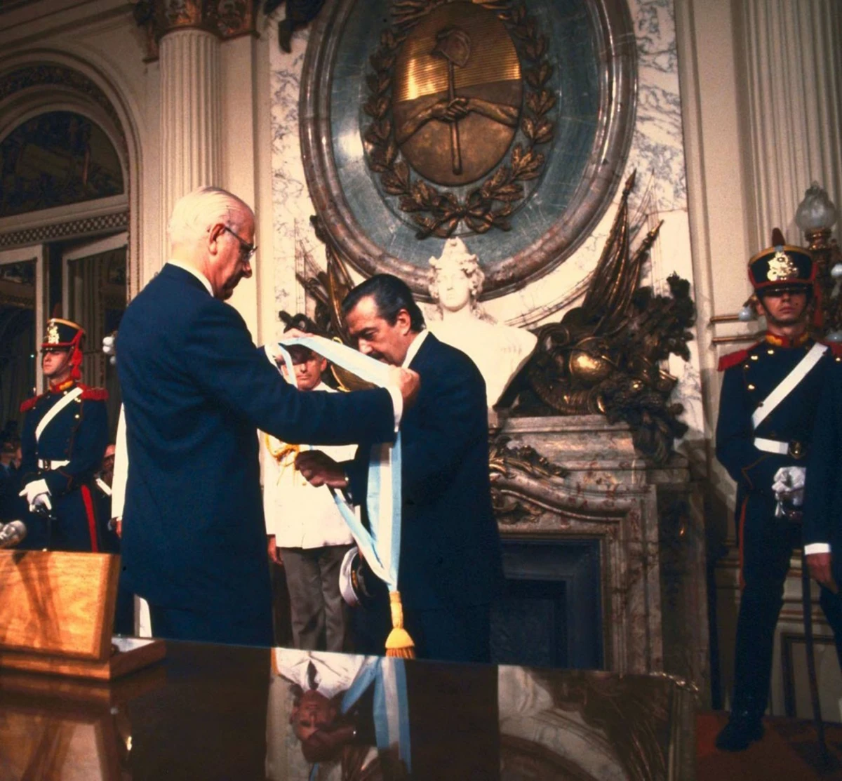 10 DE DICIEMRE DE 1983. El dictador Bignone le coloca la banda a Alfonsín. Fue el epílogo de una tensa transición. 