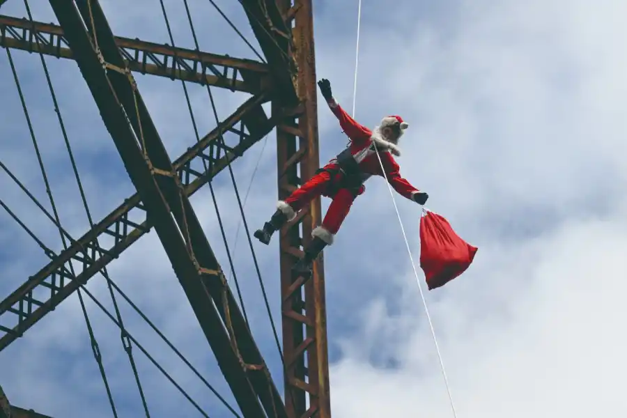 EN GUATEMALA. Héctor Chacón, bombero municipal de la capital de Guatemala, desciende desde lo alto de un puente cargando una bolsa de regalos para niños de un asentamiento popular.