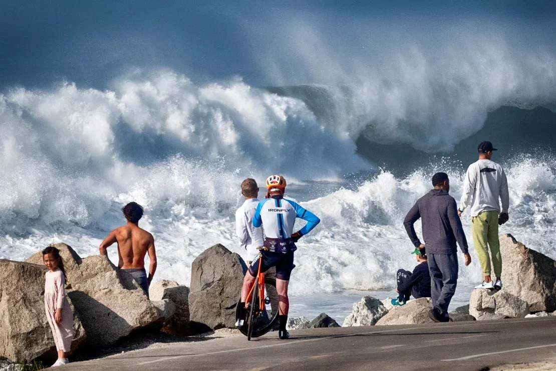 Personas observando las grandes olas que azotan Manhattan Beach en California