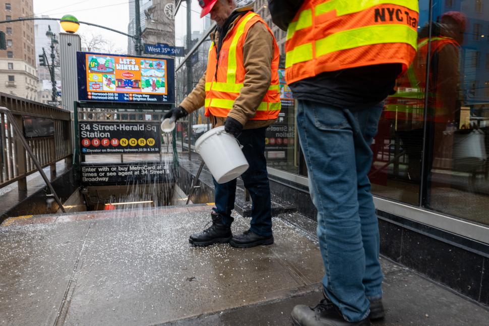 EN NUEVA YORK. Trabajadores del transporte arrojan sal en una acera para neutralizar la nevada que cubre a los Estados Unidos.