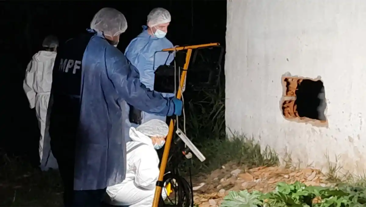 POR LA MEDIANERA. Los integrantes del ECIF analizan un hueco por el que habrían ingreso los delincuentes al predio.