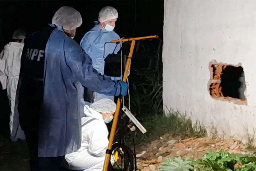 POR LA MEDIANERA. Los integrantes del ECIF analizan un hueco por el que habrían ingreso los delincuentes al predio.