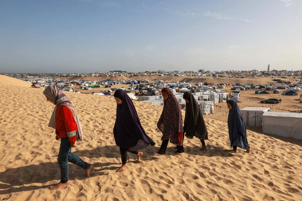 DESPLAZADAS. Un grupo de niñas palestinas camina camina por un campamento para refugiados, en Rafah.