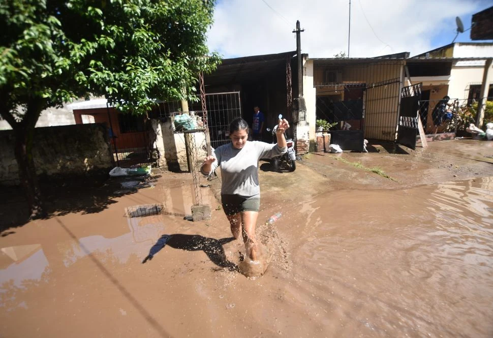 AGUA Y BARRO. Una vecina de uno de los barrios de Aguilares afectados por la tormenta sale de su casa haciendo equilibrio para no caerse. 