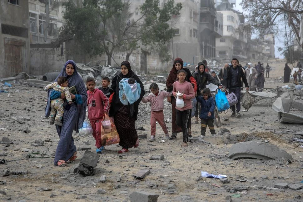HUIDA A PIE. Con los niños y sus pocas pertenencias a cuestas, mujeres palestinas huyen del área de los bombardeos, en el centro de ciudad de Gaza.  
