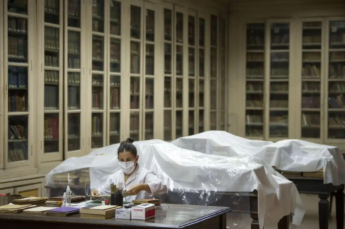 UNA EXTENSA TAREA. Detrás de Zamora y de su mesa de trabajo están los libros que ya fueron limpiados y restaurados. Queda mucho por hacer.