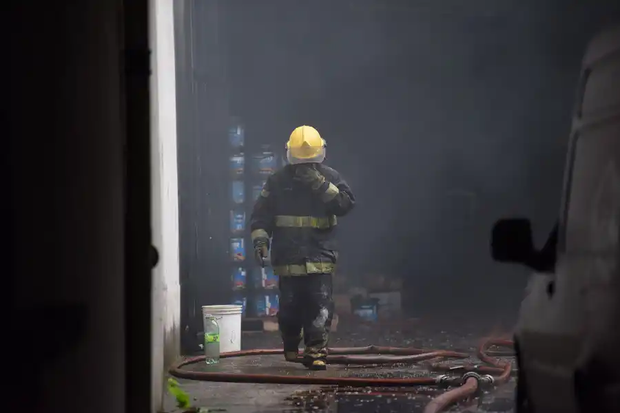 DESDE ADENTRO. Un bombero se cubre el rostro para protegerse del humo mientras sale del depósito, que sufrió daños considerables por el incendio.