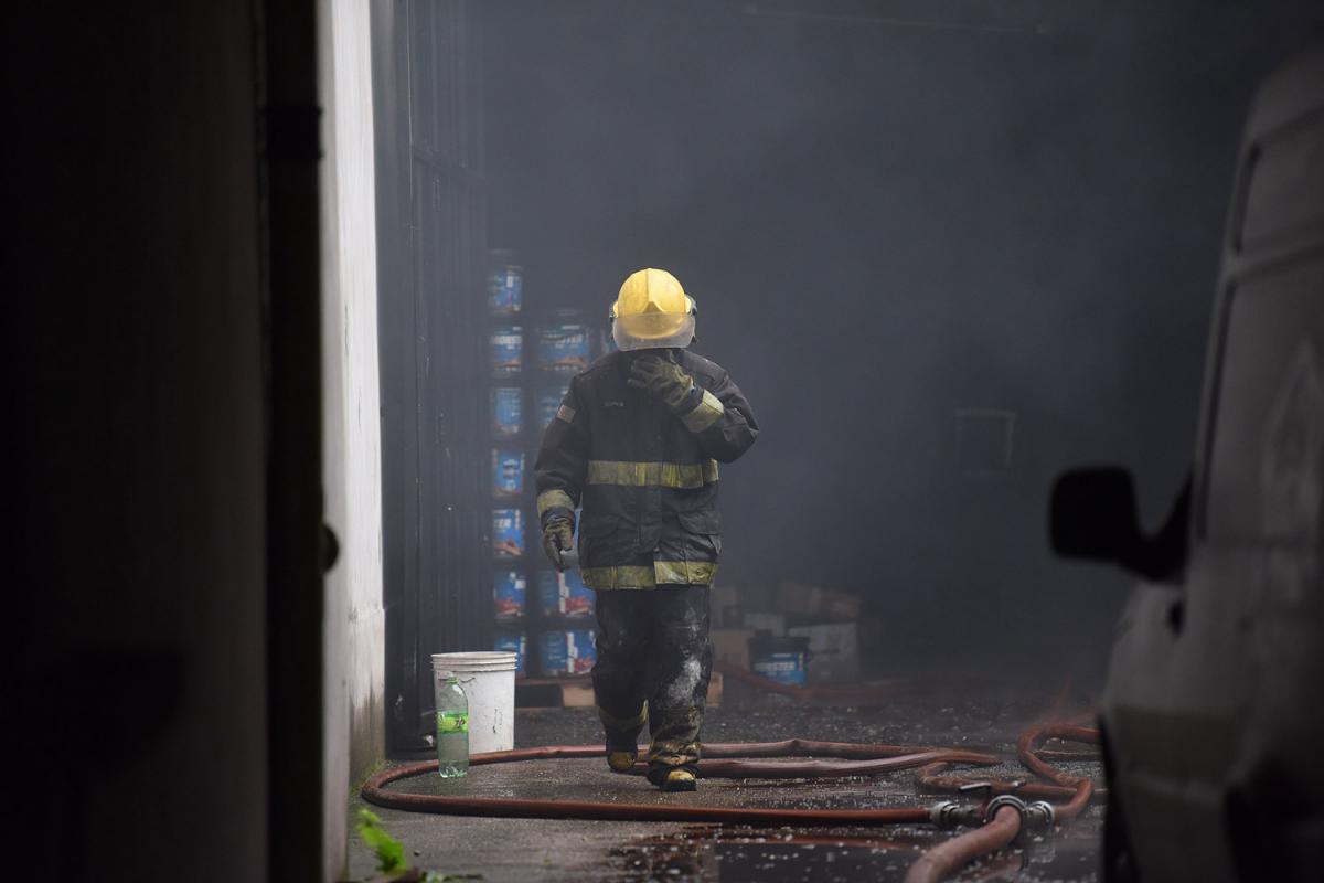 DESDE ADENTRO. Un bombero se cubre el rostro para protegerse del humo mientras sale del depósito, que sufrió daños considerables por el incendio.