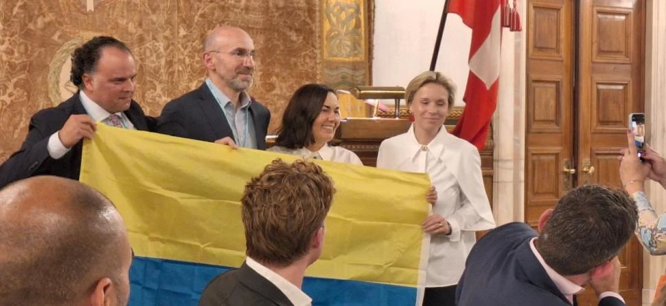 SÍMBOLO. El titular saliente de Wan-Ifra, Fernando de Yarza, despliega la bandera de Ucrania junto a Andrii Vdovychenko, Oksana Brovko y la nueva presidenta, Ladina Heigmartner.