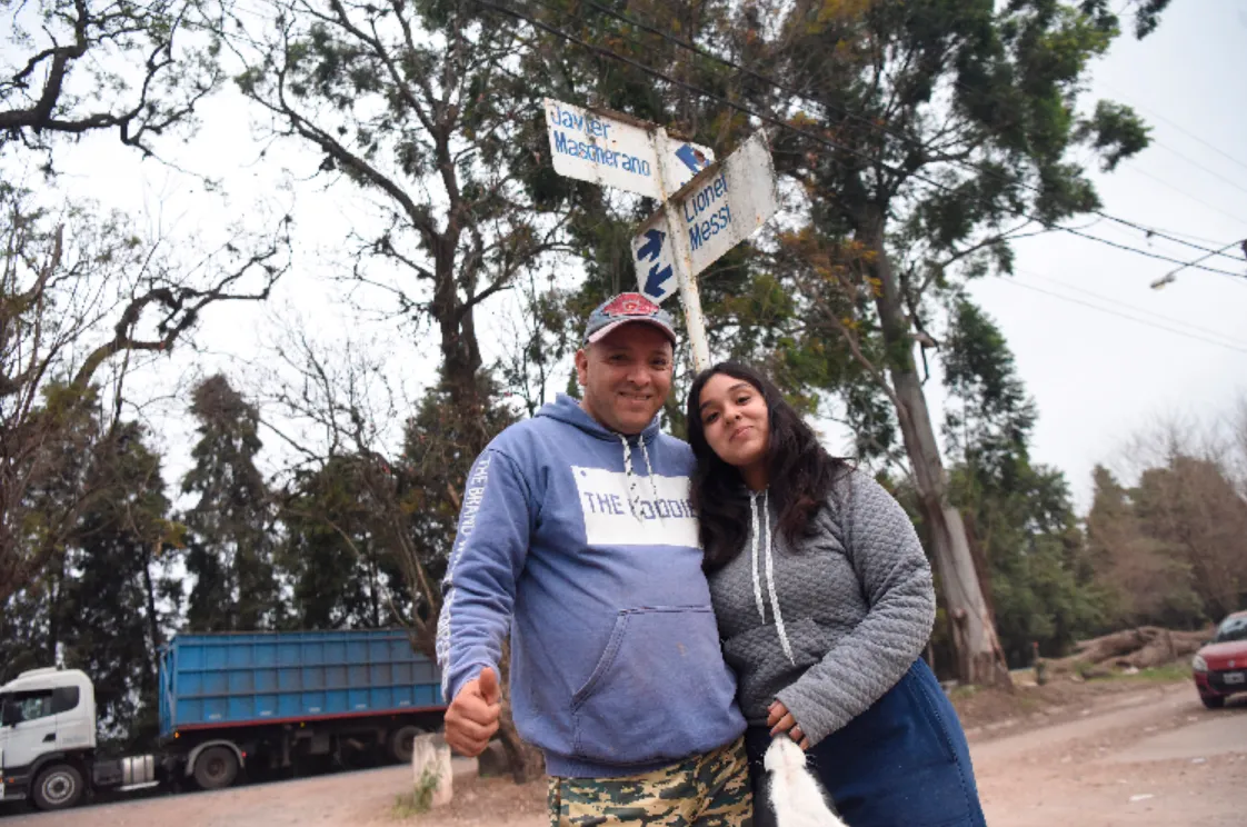 ORGULLO. Guillermo Santillán posa junto a su hija, en la esquina de Messi y Mascherano, la más emblemática del barrio El Portal de la boca del tigre, de El Chañar.