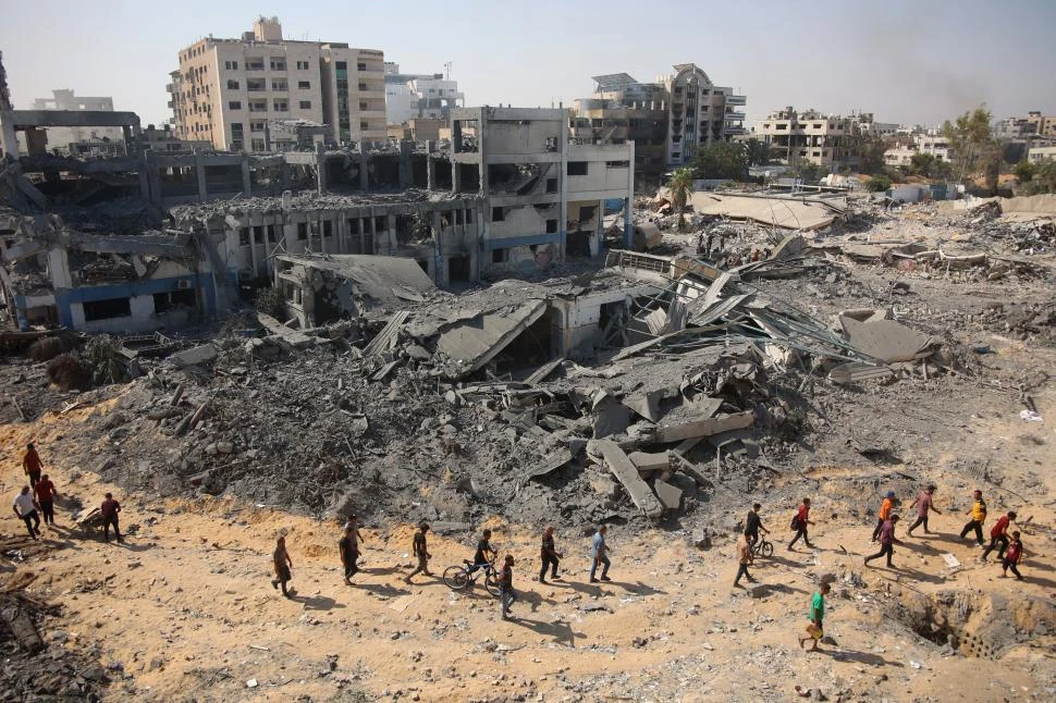 BÚSQUEDA. Un grupo de palestinos recorre las ruinas de una sede de la ONU, destruida por bombas israelíes.  AFP