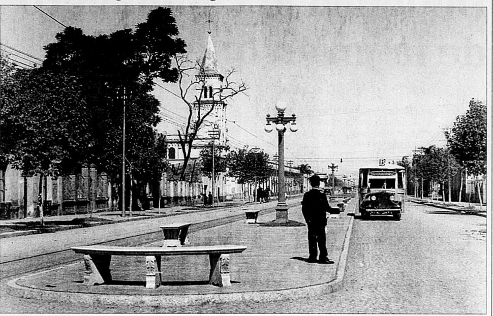 BOULEVARD AVELLANEDA EN 1930. Con la torre de San Roque de fondo un pasajero, sobre la ancha platabanda, hace señas al colectivo que viene.