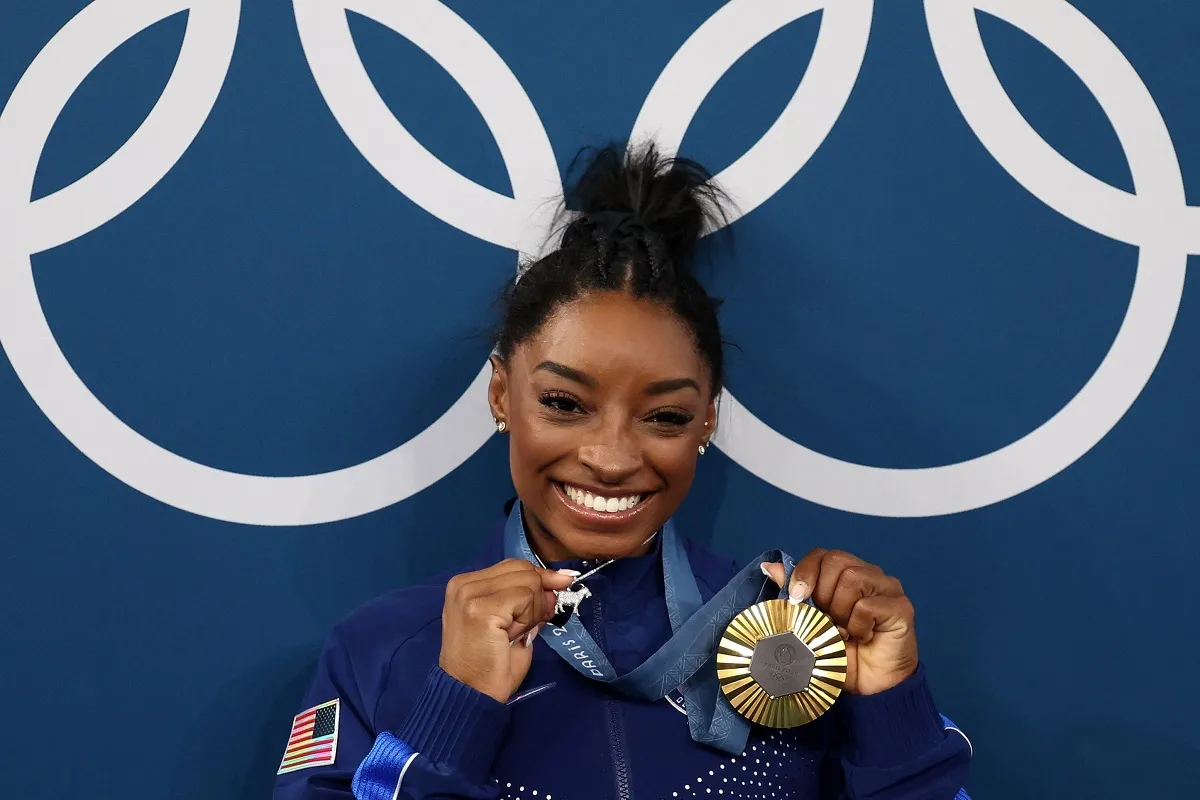 FELIZ. Simone Biles posa junto a la sexta medalla dorada que logró en su carrera. 