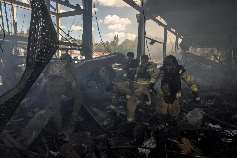 BOMBAS EN UN SUPERMERCADO. Rescatistas y militares ucranianos buscan víctimas entre los escombros.  