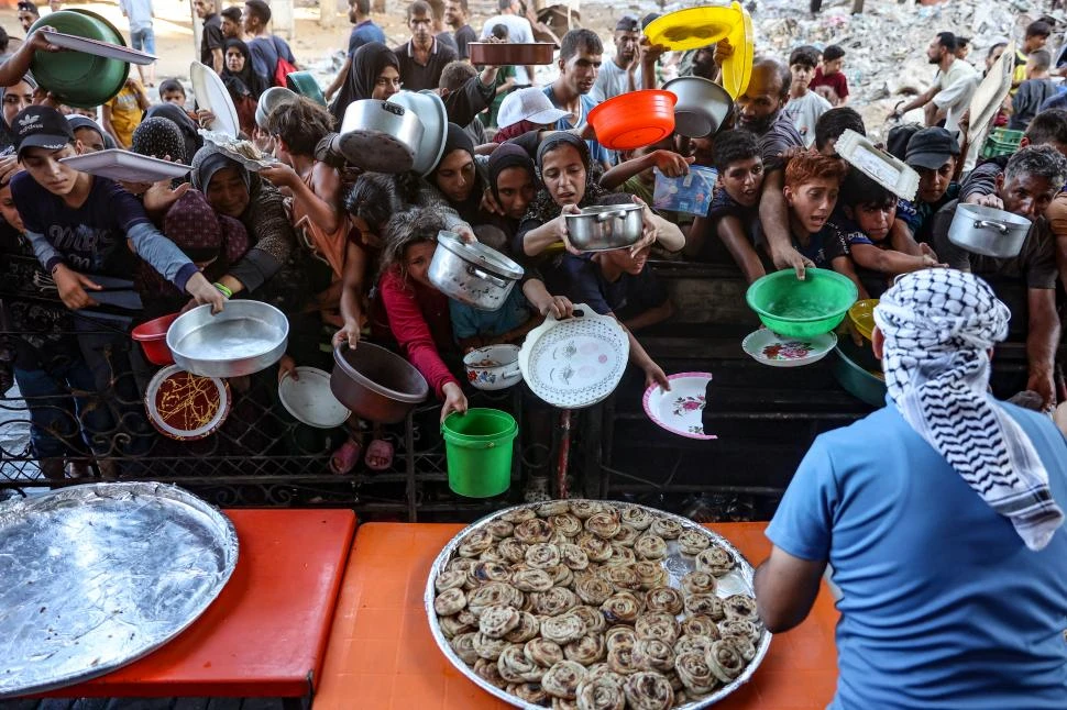 NECESIDAD EXTREMA. Decenas de personas pugnan por obtener comida en Beit Lahia, en el norte de Gaza.  