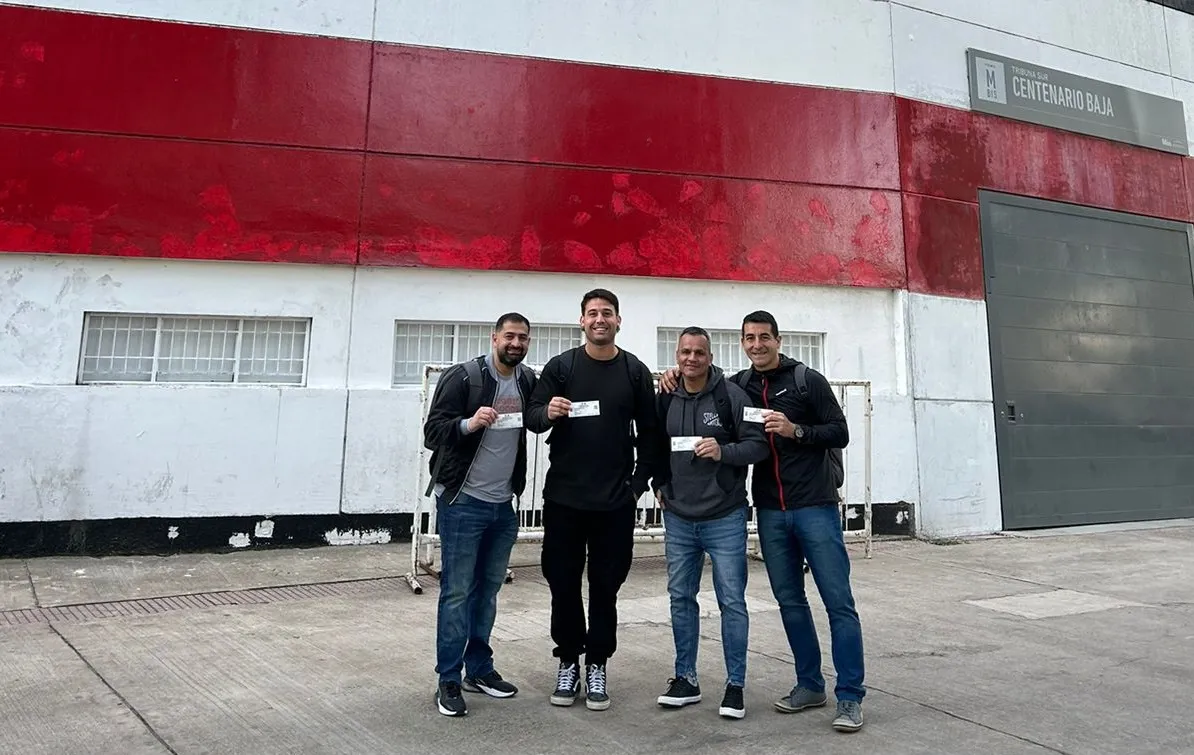 FELICES. Leonardo Sadir, Patricio Cipriani, Darío Vercellone y Ricardo Véliz posan con las entradas en la puerta del estadio de River.