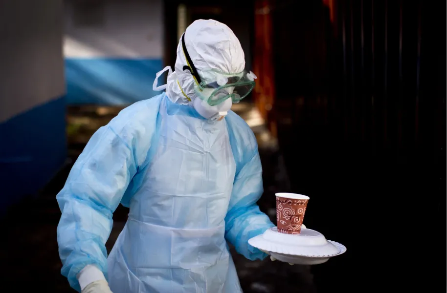 Un trabajador médico lleva comida a un paciente aislado por el virus de Marburgo durante el brote en Kenia en 2014.