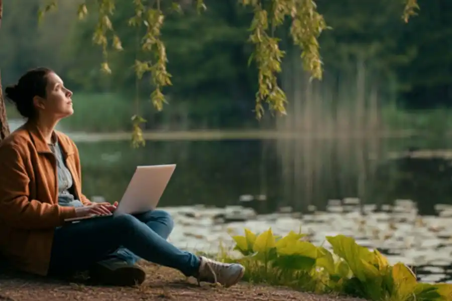 ImageFX: A solitary figure sits peacefully by a tranquil lake, surrounded by lush greenery.