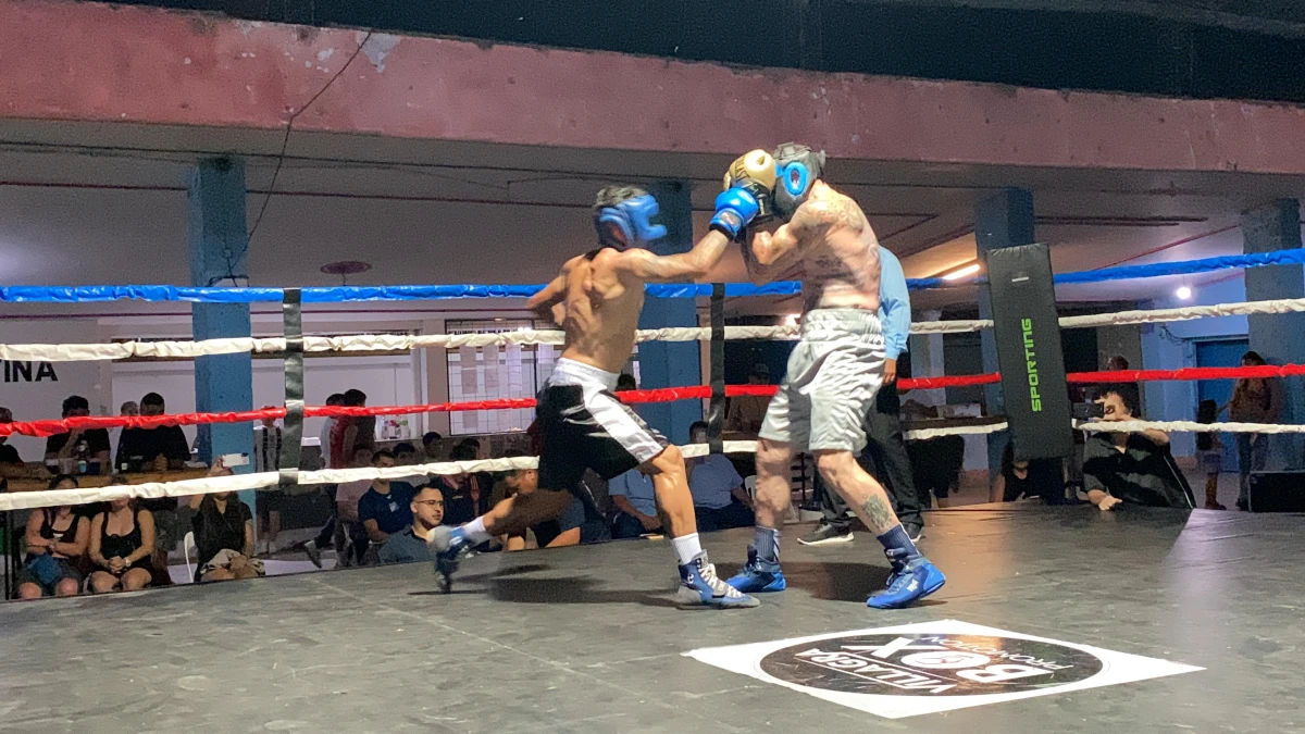  DERECHA BLOQUEADA. Orihuela (negro y blanco) intenta conectar a Casalicchio que se anticipó y cubrió su rostro. El futbolista y el boxeador animaron la noche en una exhibición en el club El Cruce.